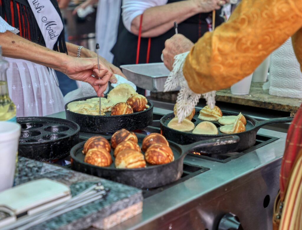 Fresh æbleskiver, traditional Danish pancake balls, cooked on cast iron griddles at Solvang Danish Days
